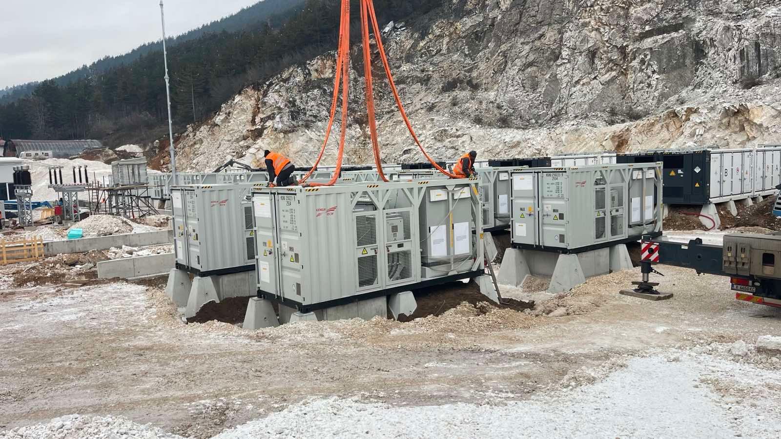Hithium battery container being lowered into place by crane during construction.